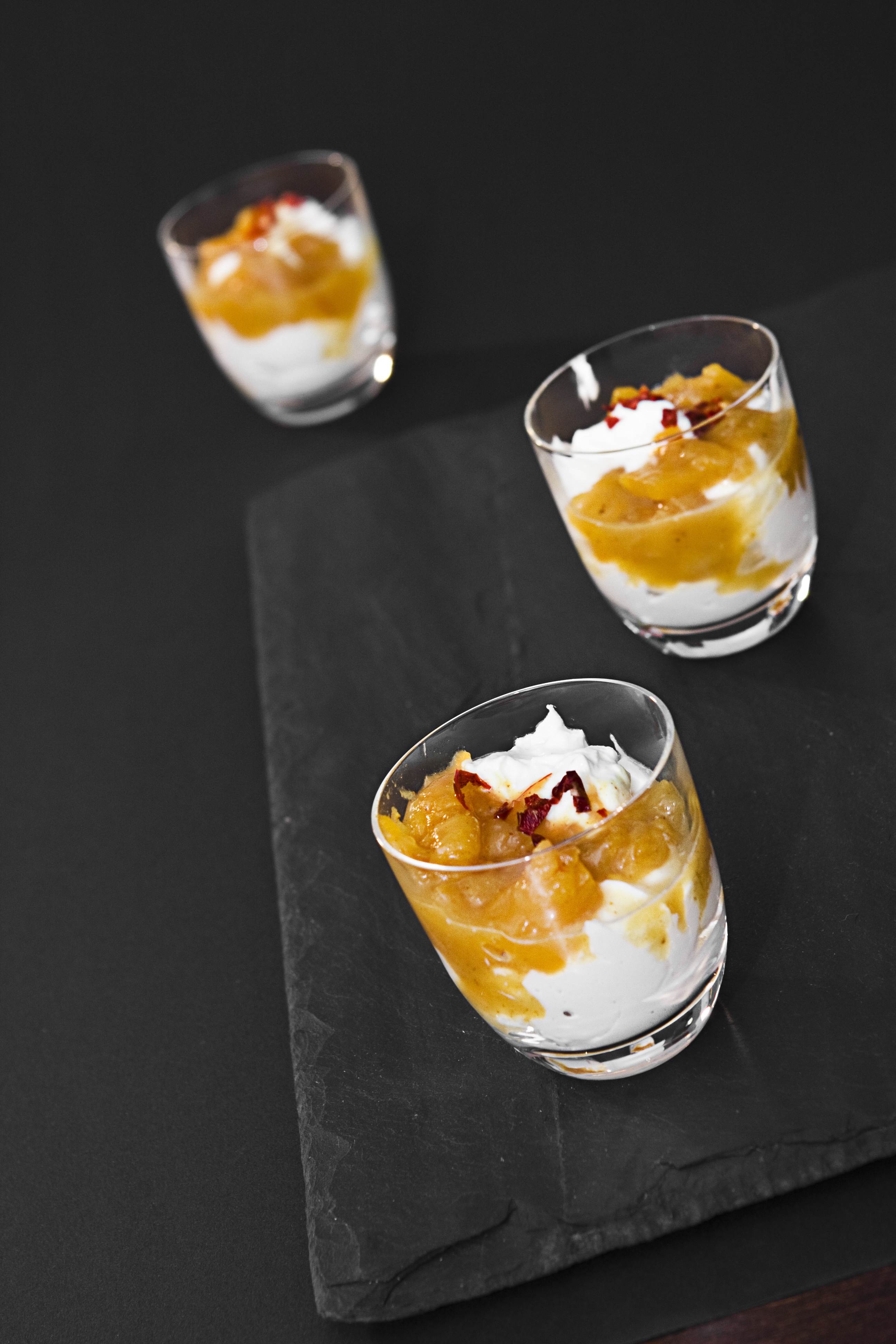 4 filled dessert glasses on a black table