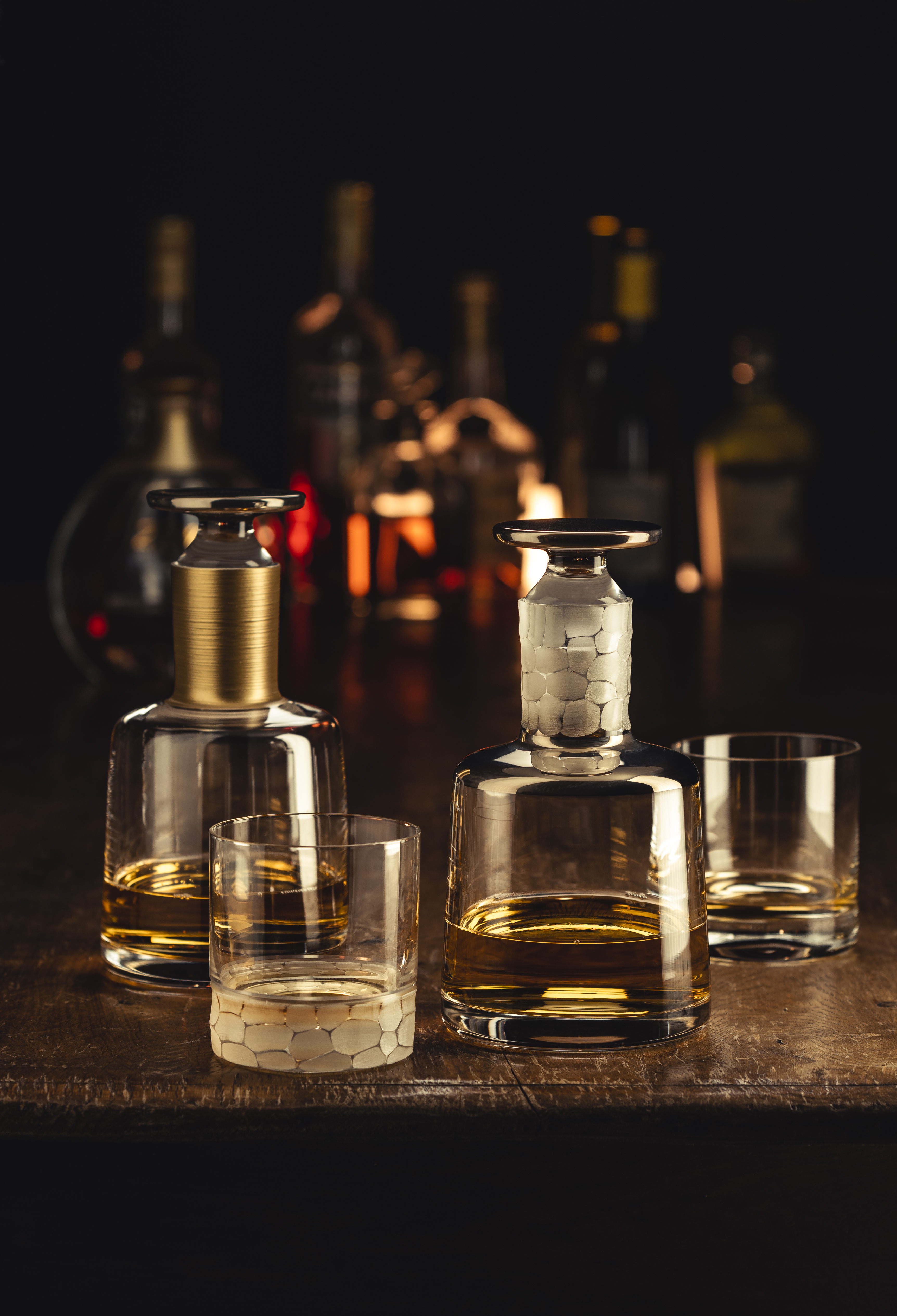 Various whisky decanters and glasses in a bar setting