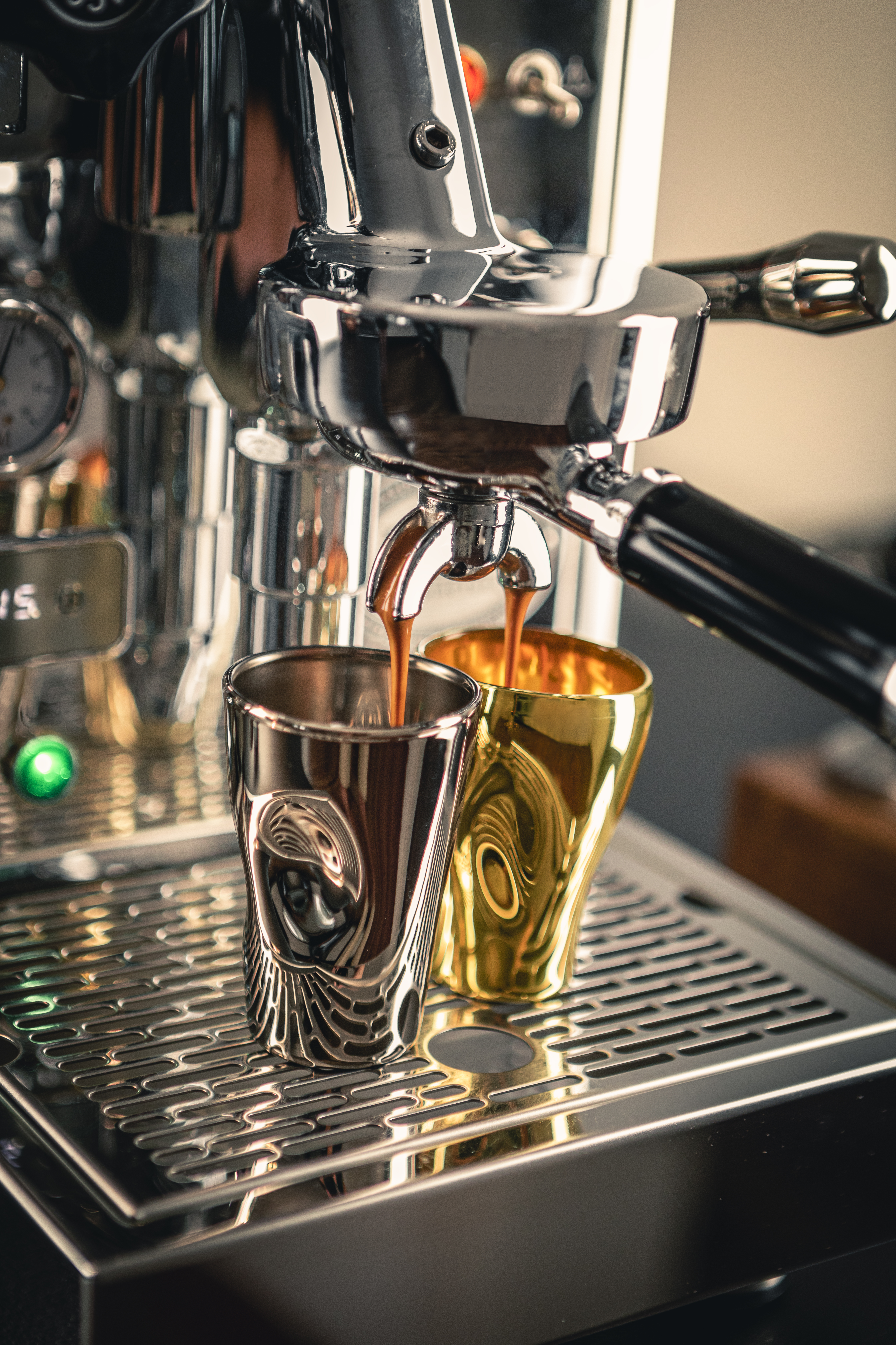 Espresso cups in platinum and gold under a coffee machine